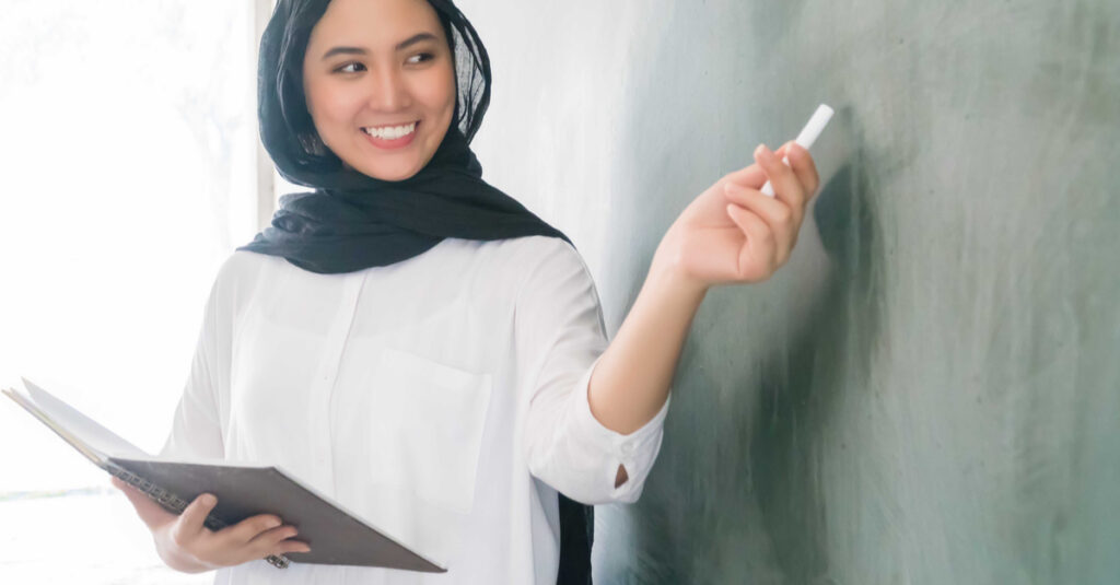 Seorang calon guru wanita muda mempresentasikan materi, simbol semangat berkarier di dunia pendidikan modern