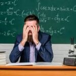 Guru Indonesia tampak lelah di depan papan tulis, menggambarkan tekanan dan pentingnya menjaga kesehatan mental guru di lingkungan sekolah.