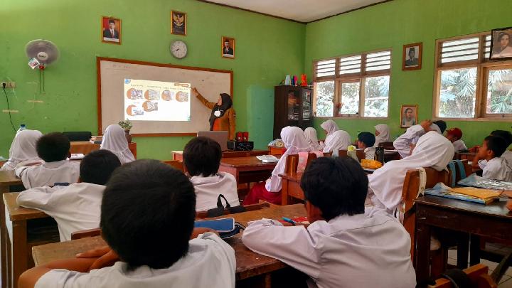 Suasana guru mengajar di kelas sebagai ilustrasi masalah kompetensi guru Indonesia pada mata pelajaran sains dan bahasa Inggris.